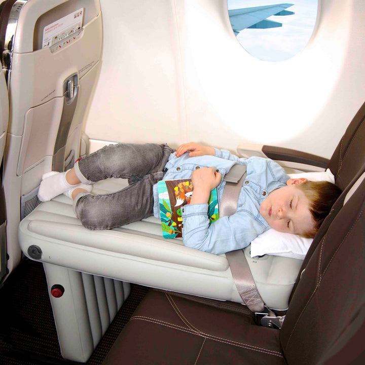 Kind auf Flyaway Kids Bed im Flugzeug, liest Buch, bequemes Reisen, Kinderbett, Flugzeugzubehör.