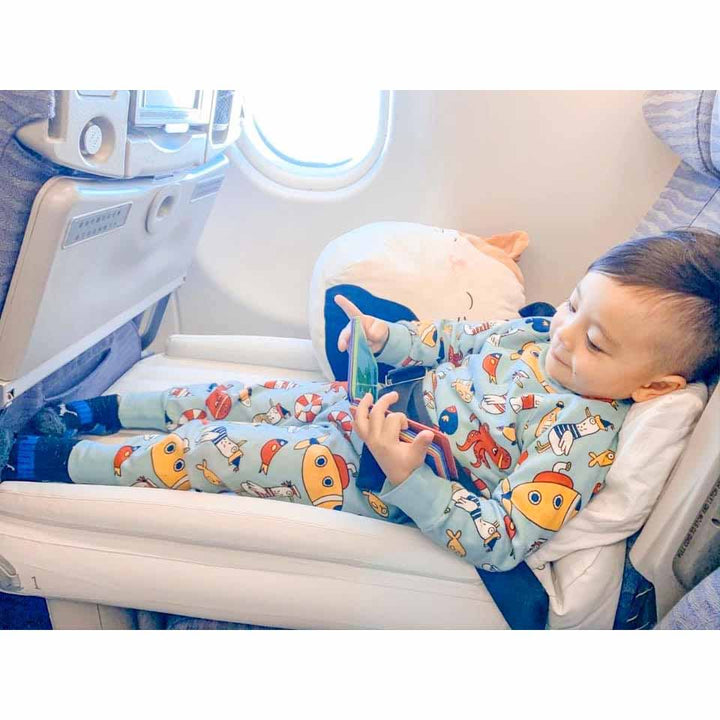 Kleinkind schläft bequem im Flugzeug auf Flyaway Kids Bed, bunte Pyjamas, Flugreise.