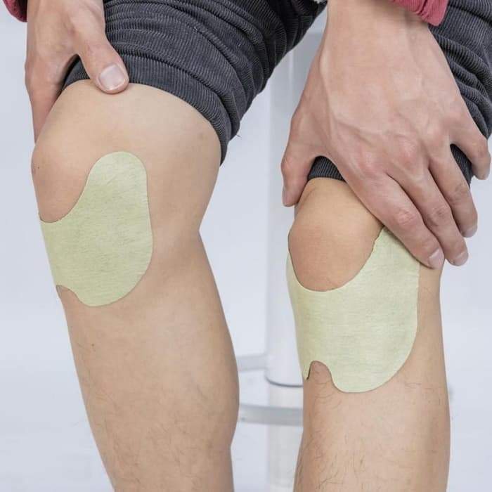 Menschliche Knie mit beige Schmerzpflastern, Schmerzlinderung, Kniebandage, Therapie.