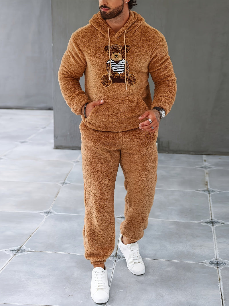 Mann in braunem Teddyfleece-Trainingsanzug mit Kapuze und Bärendesign, weiße Sneaker.