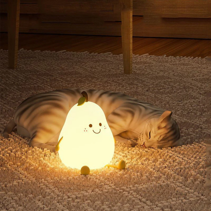 Leuchtende Birnenlampe mit Gesicht auf Teppich neben schlafender Katze, Nachtlicht Kinderzimmer.