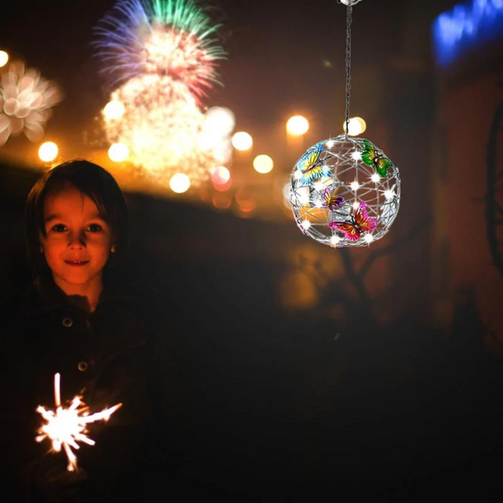 Junge mit Wunderkerze und leuchtender LED-Lampe, Feuerwerk im Hintergrund, Nachtaufnahme.