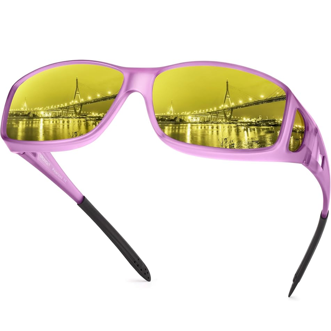 Lila Sonnenbrille mit gelben Gläsern, reflektiert beleuchtete Stadtbrücke bei Nacht.