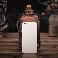 Braune Herren-Gürteltasche aus Leder, vintage Stil, mit Smartphone, auf Holztisch.