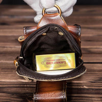 Braune Leder-Gürteltasche für Herren, geöffnet, mit Reißverschluss, auf Holztisch.