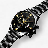 Schwarze Edelstahl-Armbanduhr mit Chronograph, goldenen Zeigern und Datumsanzeige.