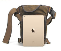 Braune Canvas-Umhängetasche mit iPad, verstellbarem Gurt, ideal für Outdoor-Aktivitäten.