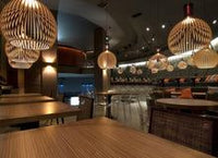 Moderne Restaurantbeleuchtung mit hölzernen Pendelleuchten über Holztischen.