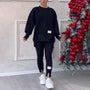 Frau in schwarzem Oversize-Sweatshirt und Leggings, weiße Sneaker, neben Weihnachtsbaum.