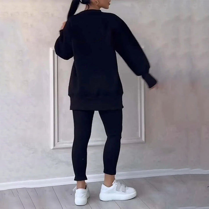 Frau in schwarzem Oversize-Pullover und Leggings, weiße Sneaker, moderne Freizeitmode.