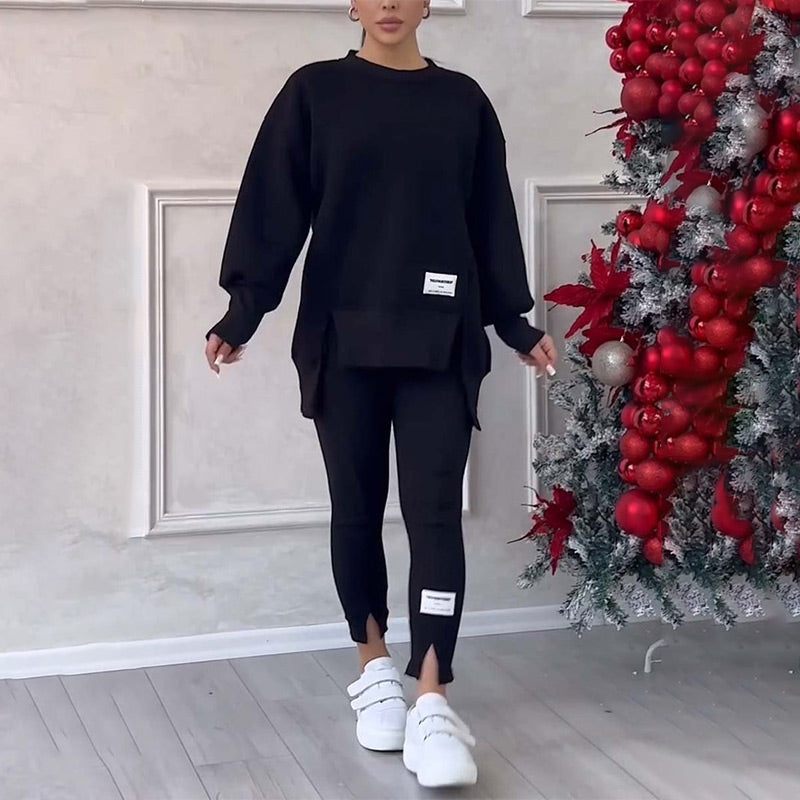 Frau in schwarzem Oversize-Sweatshirt und Leggings, weiße Sneaker, neben Weihnachtsbaum.