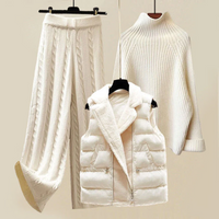 Damen Winter-Outfit: weiße Strickhose, Rollkragenpullover, gesteppte Weste.