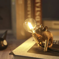 Goldene Mauslampe mit Glühbirne, dekorative Tischleuchte, Vintage-Stil, warmes Licht.