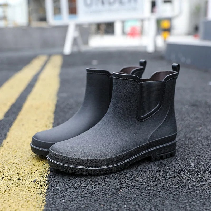 Schwarze Chelsea-Gummistiefel, wasserdicht, rutschfest, für Damen und Herren, auf Asphalt.